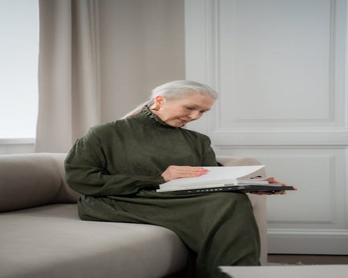 Mature woman comfortably reading a book in a bright room